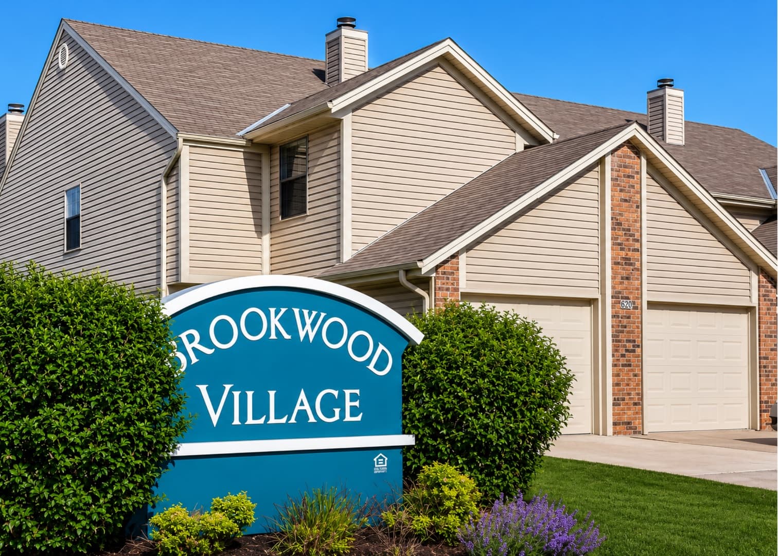 Brookwood Village entrance sign surrounded by landscaping with townhomes behind